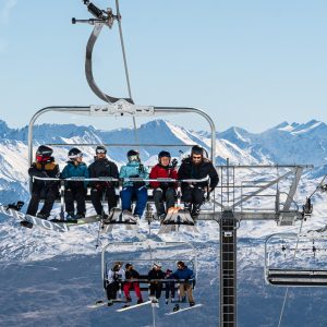 a group of people riding a ski lift on top of a snow covered mountain